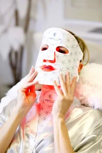 Close-up of a woman wearing an ILUMILUX LED mask demonstrating red, blue and near-infrared lights for anti-aging and acne.